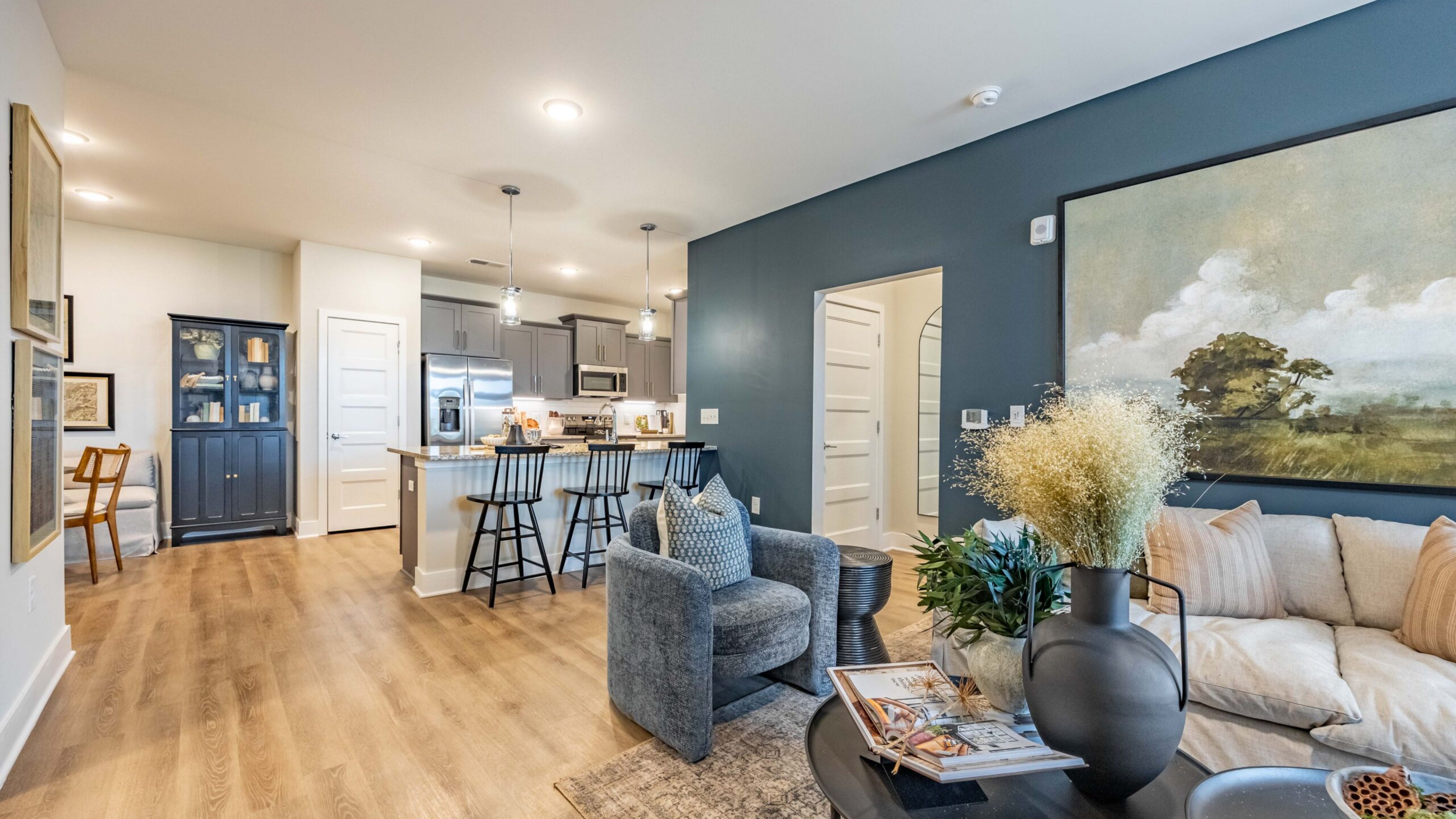 Hawthorne at Brightwood Farm spacious kitchen with white cabinetry, a large island with bar seating, modern pendant lighting, and hardwood floors.
