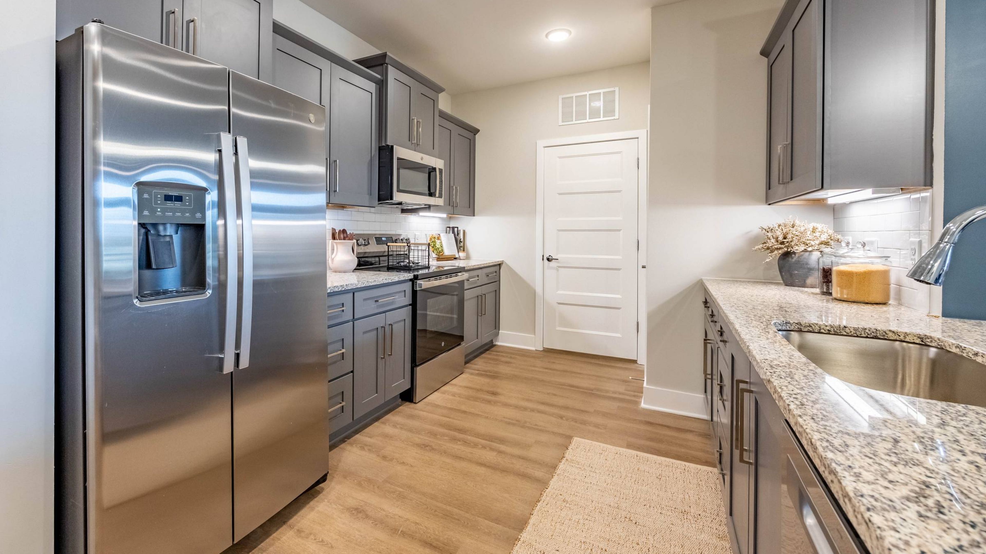 Hawthorne at Brightwood Farm spacious kitchen with white cabinetry, a large island with bar seating, modern pendant lighting, and hardwood floors.