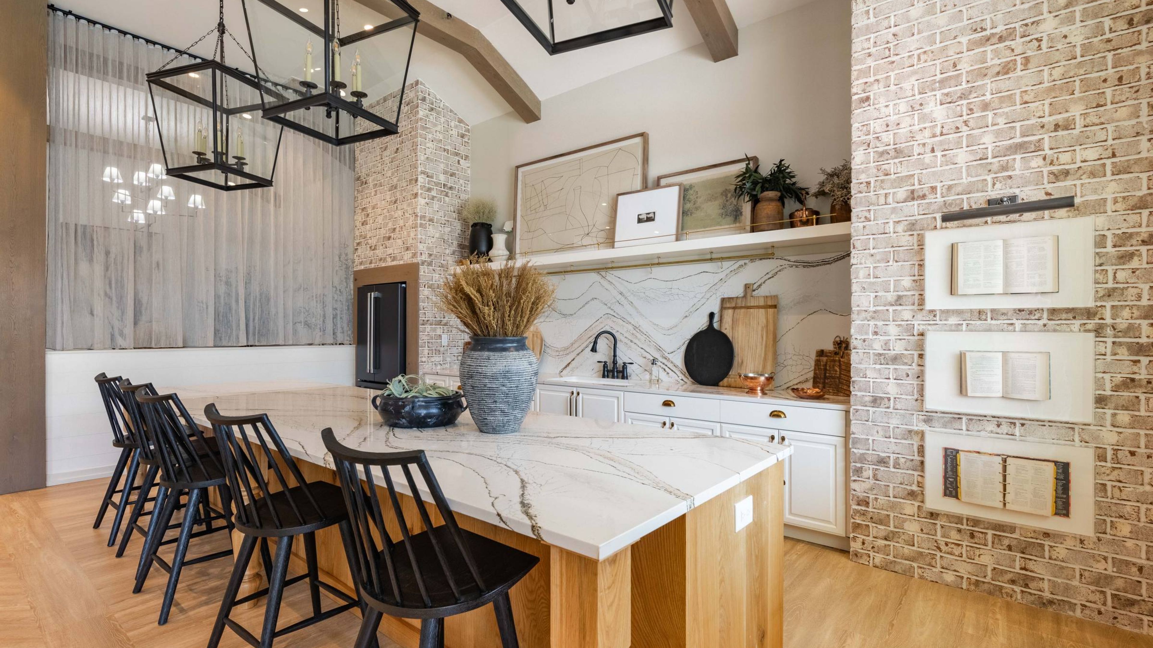 Hawthorne at Brightwood Farm stylish kitchen area showcasing a large island with seating, modern light fixtures, and rustic brick accents.